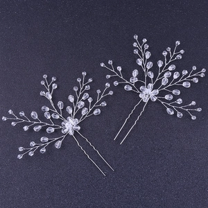 Detailed view of two silver bridal hair pins with clear crystals on a blue surface