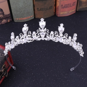 Silver bridal crown with rhinestone scrolls and teardrop crystals on a dark background