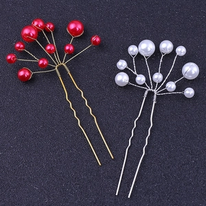 Dettaglio di forcine a U fatte a mano con perle rosse e bianche per acconciature sposa
