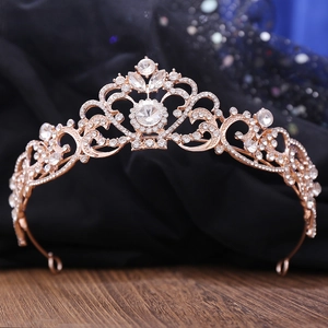 Elegant rose gold bridal crown with shimmering white rhinestones on a wooden surface