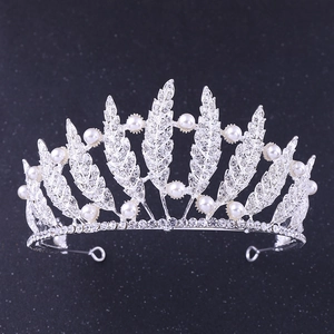 Close-up of bridal leaf tiara with sparkling rhinestones and white pearls on silver band
