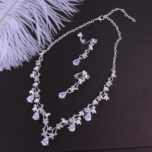 Macro detail of bridal jewelry set with silver necklace and pear-shaped zircon earrings