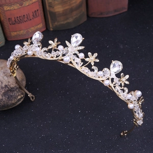 Détail d'un diadème de mariée doré orné de fleurs en cristal et de perles sur fond noir