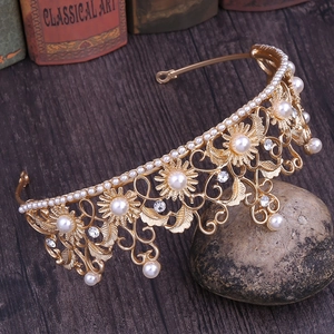 Close-up of golden baroque crown with intricate leaf patterns and white faux pearls