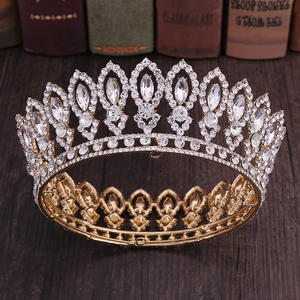 Close-up of golden baroque bridal crown with crystals on a dark vintage wooden desk