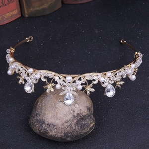 Détail d'une couronne dorée ornée de perles blanches et de cristaux suspendus en goutte