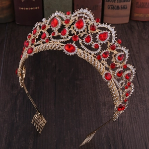 Close-up of golden bridal tiara with red crystals and hair comb on vintage wooden desk