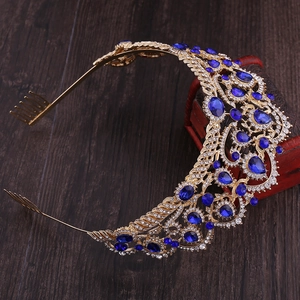 Close-up of a vintage bridal crown with dark blue crystals and golden comb on a wooden box