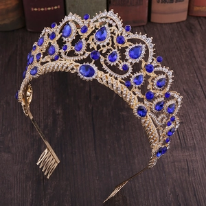 Close-up of golden bridal crown with blue teardrop crystals and combs on wood surface