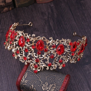 Detail of vintage gold bridal crown with red rhinestones on an antique wooden chest