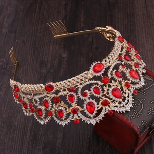 Detail of elegant gold crown with red crystals and intricate openwork on wood background