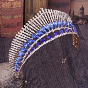 Close-up of peacock-style gold crown featuring blue teardrop crystals and sparkling rhinestones