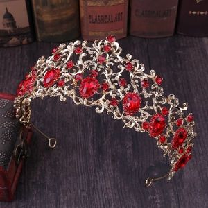 Close-up of golden bridal tiara with red rhinestones on a vintage wooden desk background