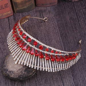 Close-up of golden bridal crown featuring red pear-shaped crystals and peacock tail design