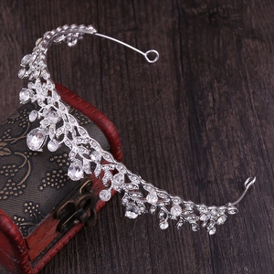 Macro detail of leaf-patterned silver tiara with rhinestones on a vintage wooden box