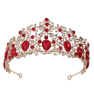 Detail view of gold tiara featuring ruby red crystals and intricate openwork leaf patterns