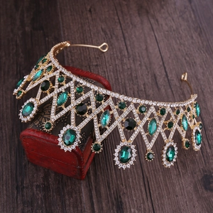 Détail d'une couronne de mariée dorée avec strass vert émeraude sur boîte à bijoux