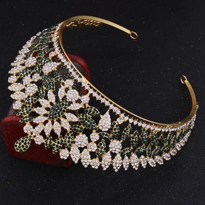 Detail of golden metal crown with inlaid emerald green and white rhinestones