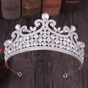 Détail d'une couronne baroque argentée sertie de strass posée sur un support en bois