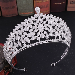 Macro shot of silver rhinestone crown with intricate floral patterns on black surface