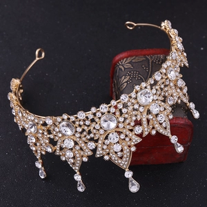 Macro shot of gold bridal crown with crystal teardrops on vintage red wooden chest
