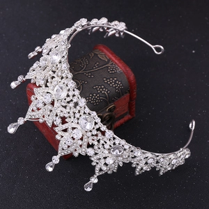 Baroque silver bridal tiara with crystals placed on a vintage red wooden jewelry box