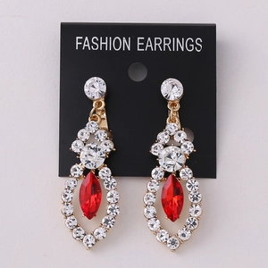 Macro detail of gold earrings with red marquise stone and white rhinestones on card