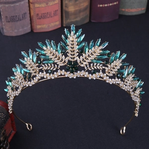Detail of vintage gold crown with emerald green crystals and leaf patterns