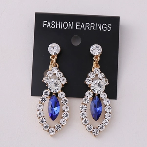 Detailed macro view of vintage gold earrings with blue marquise stone and sparkling rhinestones