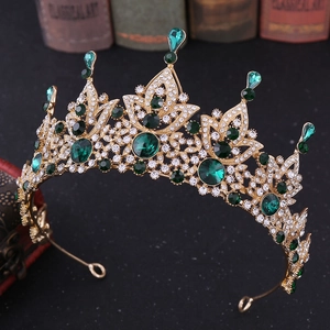 Detailed macro view of baroque vintage gold crown with emerald green gems and tiny diamonds