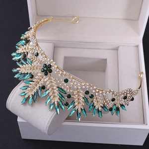 Close-up of luxury gold crown with emerald green crystals and sparkling white rhinestones