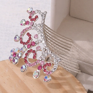 Détail d'un peigne à cheveux argenté avec strass roses et motifs floraux ciselés