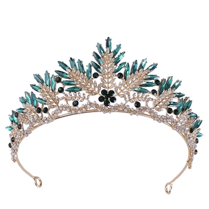 Close-up of vintage gold bridal crown with emerald green gems and black floral accents
