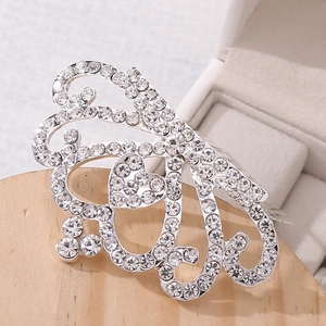 Detailed close-up of a silver rhinestone crown hair comb with heart and scroll patterns