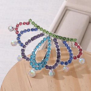 Close-up of colorful rhinestone crown hair comb on a wooden base showing fine details