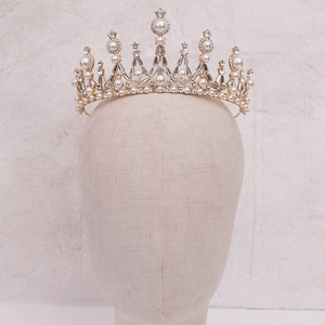 Detail view of a luxury bridal crown with white pearls and sparkling crystals on gold base