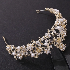 Close-up of golden bridal tiara with floral vine design, pearls and sparkling rhinestones