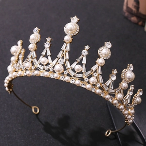 Close-up of golden baroque crown with white crystals and pearls for bridal wedding hairstyles