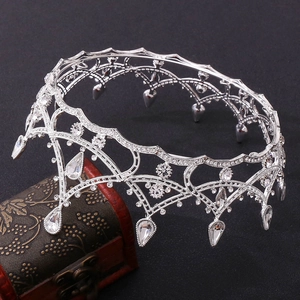 Close-up of vintage silver bridal crown with intricate hollow weave and crystal teardrops