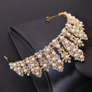 Dettaglio della corona da sposa dorata con strass scintillanti e perle bianche