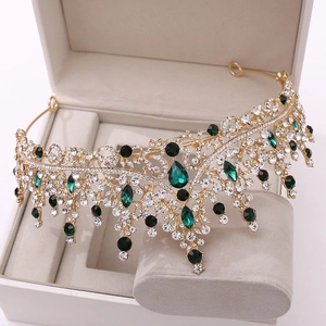 Vue détaillée d'une couronne baroque dorée avec pierres vert émeraude et cristaux blancs