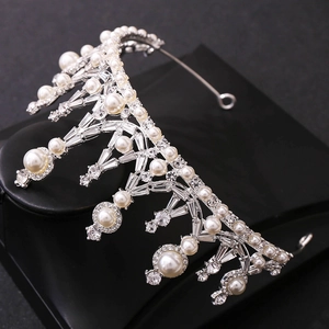 Detailed view of bridal crown featuring shimmering rhinestones and white pearls on silver base