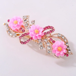 Nahaufnahme einer eleganten Gold-Haarklammer mit rosa Harzblüten und Glitzersteinen