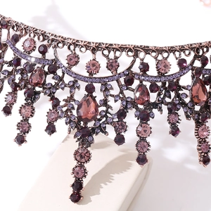 Détail macro d'une couronne baroque avec strass rouges, filigrane bronze et perles