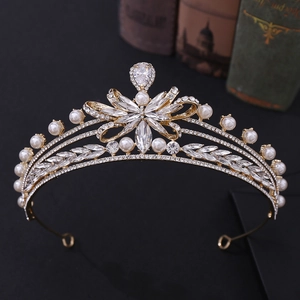 Close-up of golden bridal crown with sparkling rhinestones and white pearls on dark background