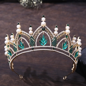 Gros plan d'une couronne de mariée dorée avec cristaux émeraude et perles sur bois