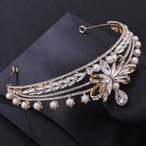 Close-up of golden bridal crown with white pearls, zircons, and a water drop pendant