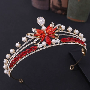 Detailed macro view of bridal tiara featuring red crystals and white pearls in gold
