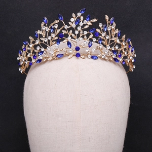 Golden bridal crown with blue leaf-shaped stones and crystals on a dark background