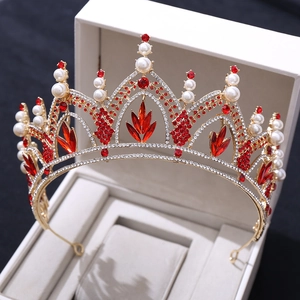 Détails macro d'une couronne dorée avec cristaux rouges et perles blanches en boîte